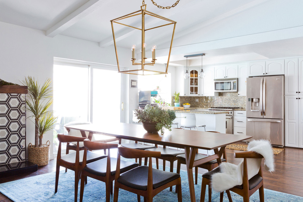 Foto di una sala da pranzo aperta verso la cucina minimalista di medie dimensioni con pareti bianche e parquet scuro
