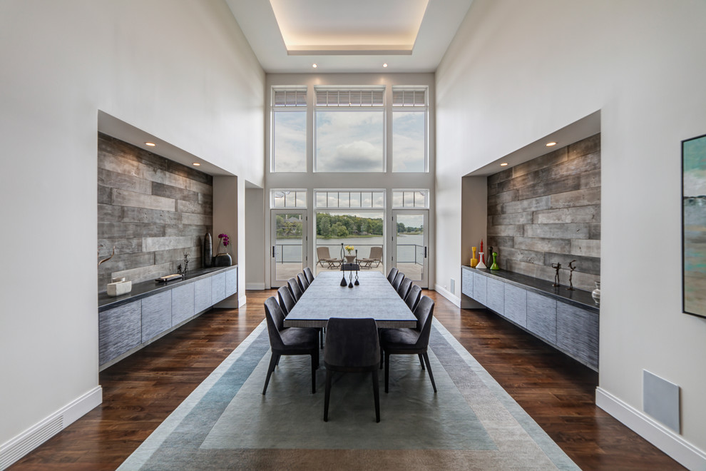 На фото: огромная кухня-столовая в стиле неоклассика (современная классика) с белыми стенами, темным паркетным полом и коричневым полом без камина с