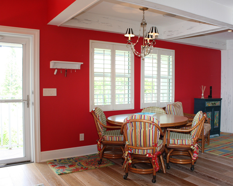 Foto de comedor costero de tamaño medio abierto sin chimenea con paredes rojas y suelo de madera clara