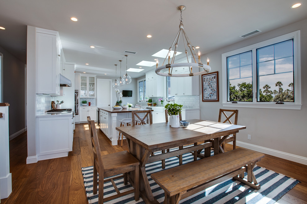 Immagine di una grande sala da pranzo aperta verso la cucina stile marinaro con pareti beige, pavimento in legno massello medio, nessun camino e pavimento marrone