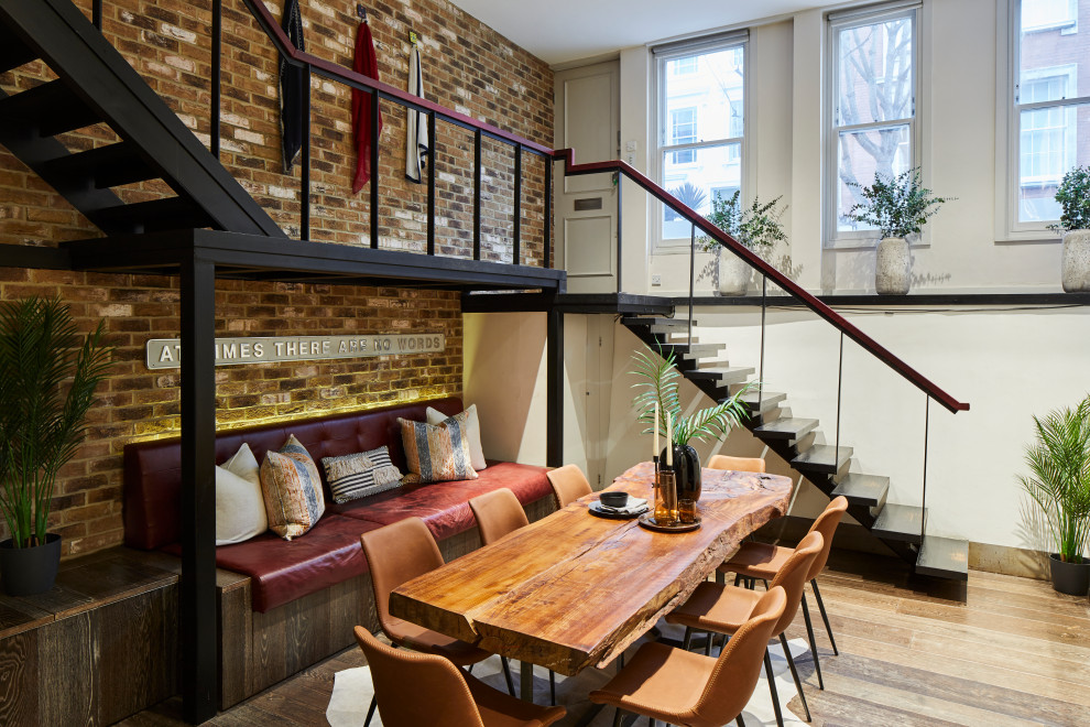 Small contemporary open plan dining room in London with white walls, medium hardwood flooring, no fireplace, brown floors and brick walls.