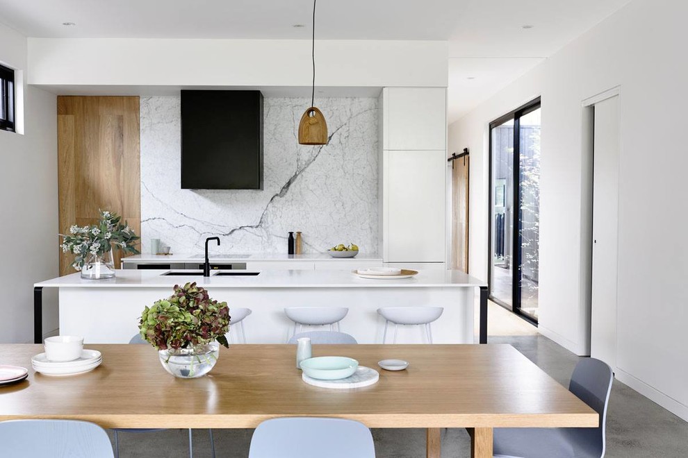 Immagine di una sala da pranzo aperta verso il soggiorno contemporanea di medie dimensioni con pareti bianche e pavimento in cemento