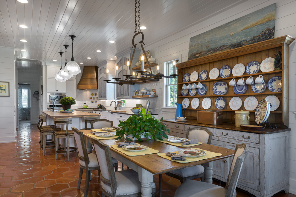 Стильный дизайн: кухня-столовая в стиле кантри с белыми стенами, полом из терракотовой плитки и оранжевым полом - последний тренд