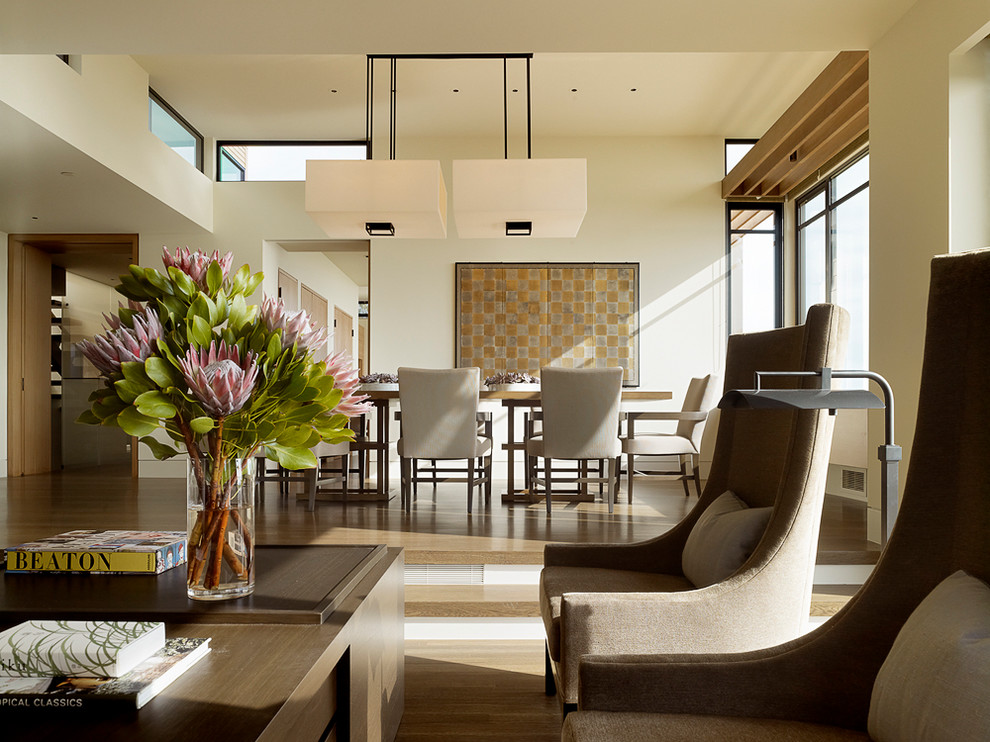 Cette image montre une salle à manger ouverte sur le salon design de taille moyenne avec un mur blanc, un sol en bois brun, une cheminée ribbon et un sol marron.