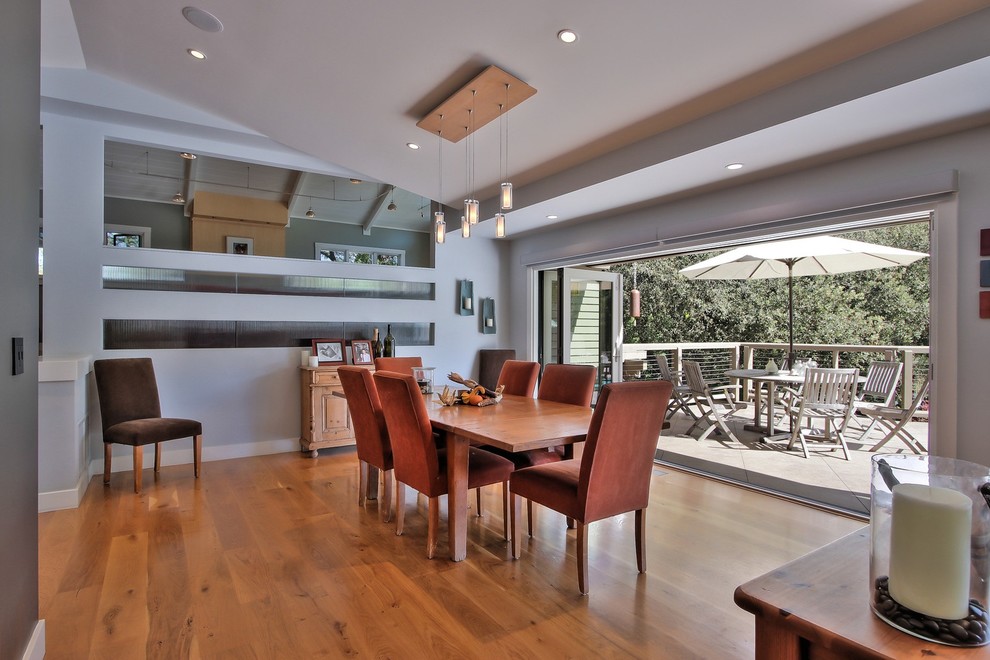 Esempio di una sala da pranzo aperta verso il soggiorno minimal con parquet chiaro, camino classico e cornice del camino in cemento