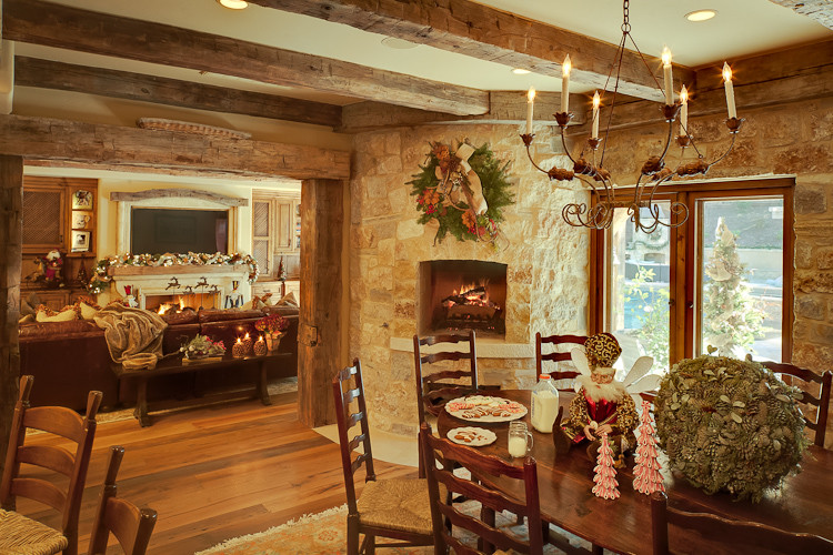 Idées déco pour une salle à manger montagne avec un sol en bois brun, une cheminée d'angle et un manteau de cheminée en pierre.