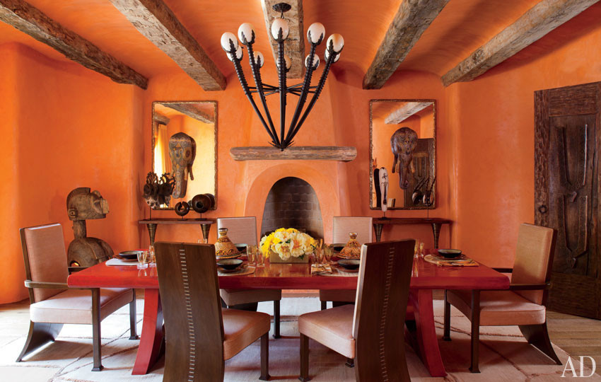 Exemple d'une très grande salle à manger éclectique fermée avec un mur orange et sol en béton ciré.