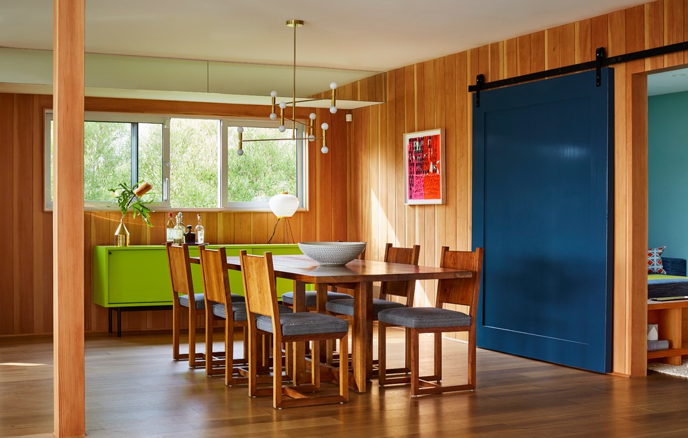 Exemple d'une salle à manger rétro avec un mur orange, un sol en bois brun et aucune cheminée.