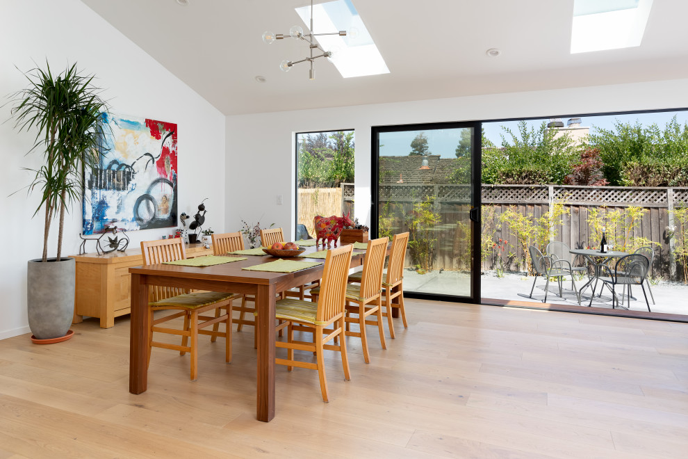 This is an example of a large contemporary open plan dining room in San Francisco with white walls, light hardwood flooring and beige floors.