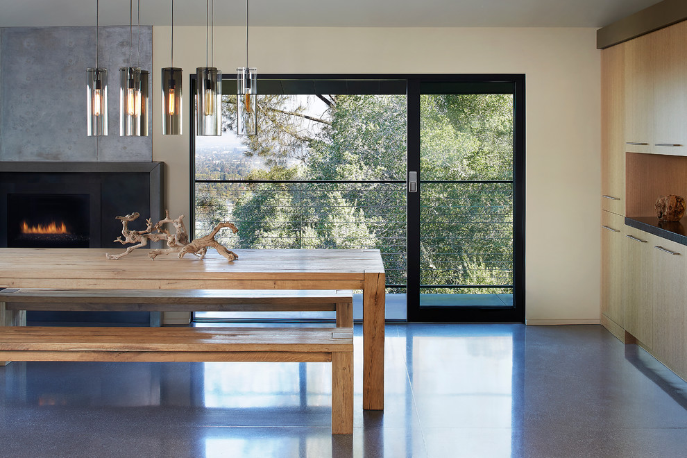 Photo of a medium sized modern open plan dining room in San Francisco with beige walls, concrete flooring, a ribbon fireplace and a metal fireplace surround.