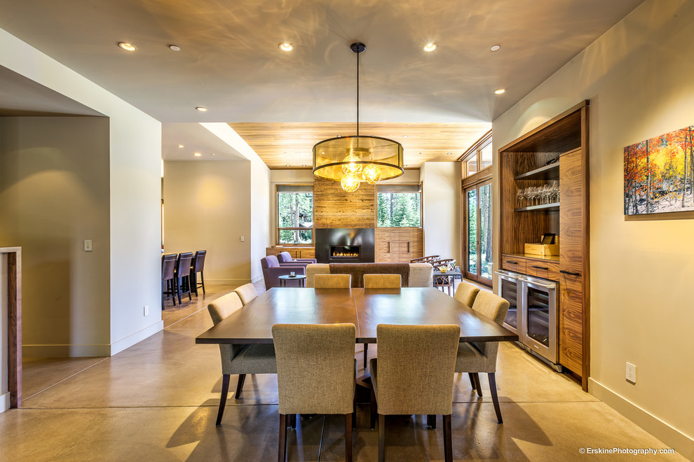 Foto di una sala da pranzo aperta verso la cucina minimal di medie dimensioni con pareti beige, pavimento in cemento, camino classico e cornice del camino in legno