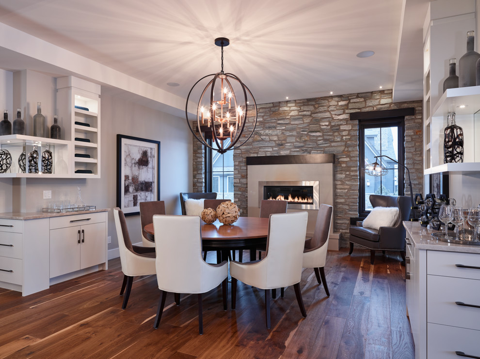 Design ideas for a traditional dining room in Calgary with medium hardwood flooring and a stone fireplace surround.