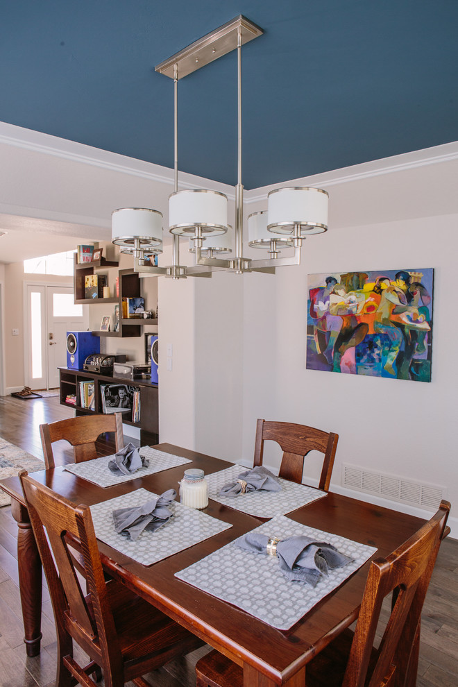 Exemple d'une salle à manger ouverte sur le salon chic de taille moyenne avec un mur blanc, un sol en bois brun et un sol marron.