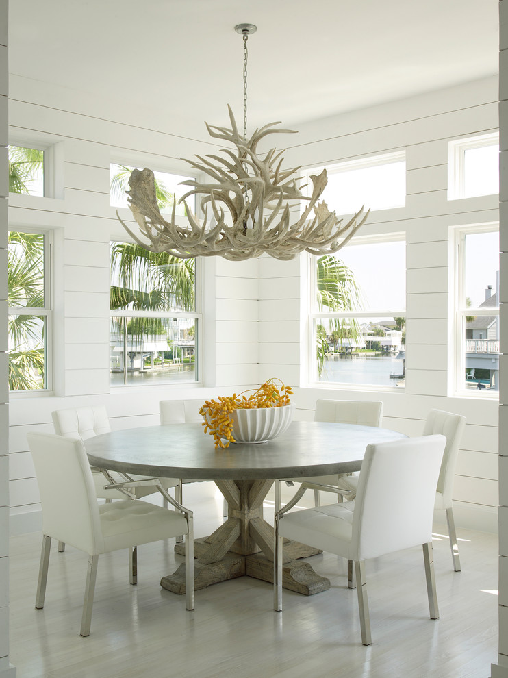 Inspiration for a beach style dining room in Houston with white walls and light hardwood flooring.