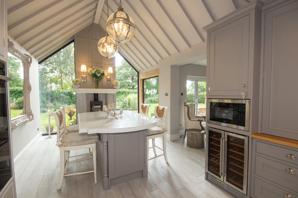 Foto de comedor de estilo de casa de campo de tamaño medio abierto con paredes beige, suelo de madera clara, estufa de leña y marco de chimenea de madera