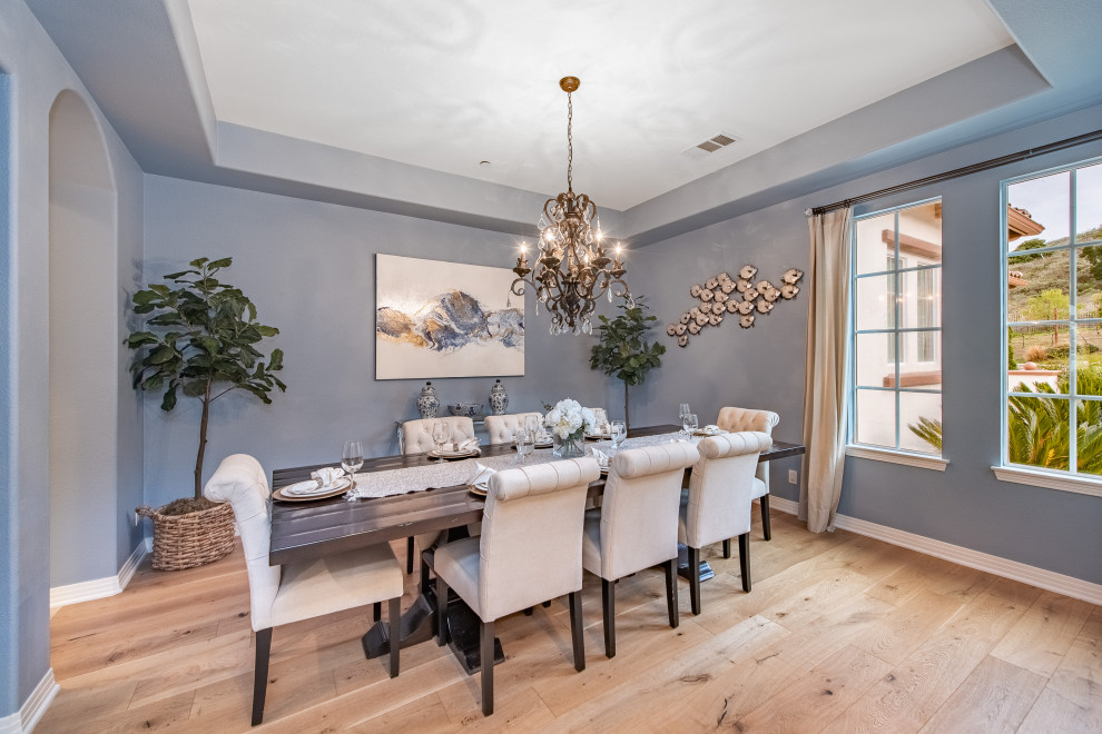 Immagine di un'ampia sala da pranzo mediterranea chiusa con pareti blu, parquet chiaro e pavimento beige