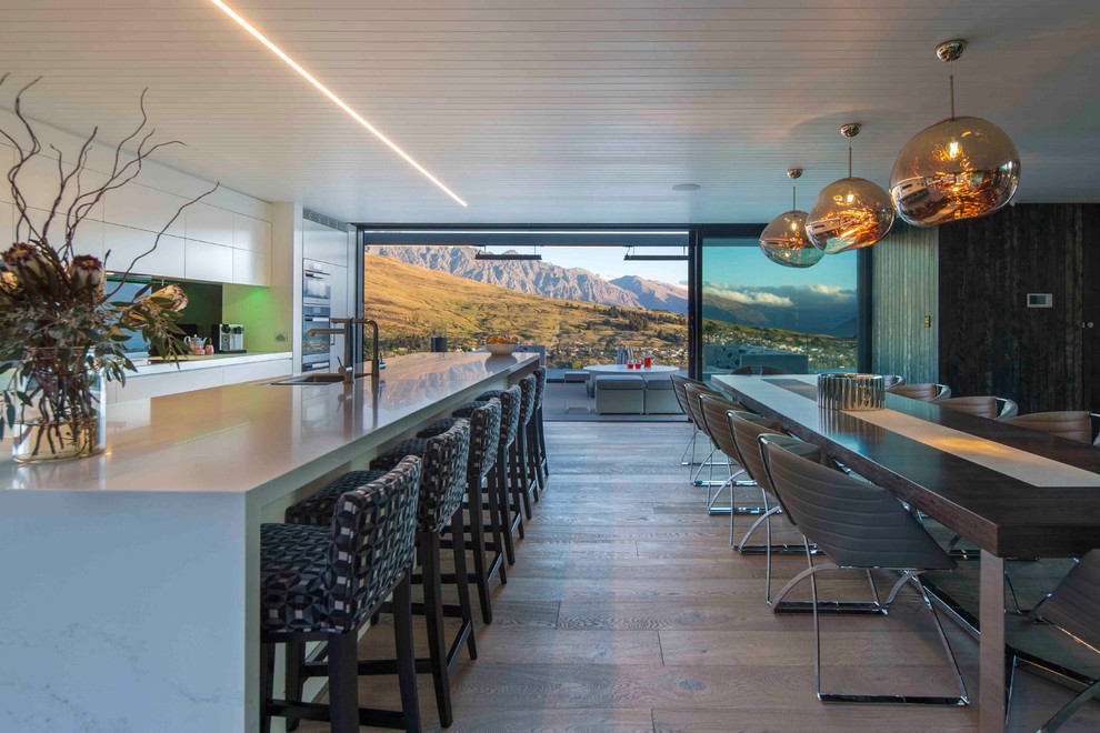 Aménagement d'une grande salle à manger ouverte sur la cuisine contemporaine avec un mur multicolore, un sol en bois brun et un sol beige.
