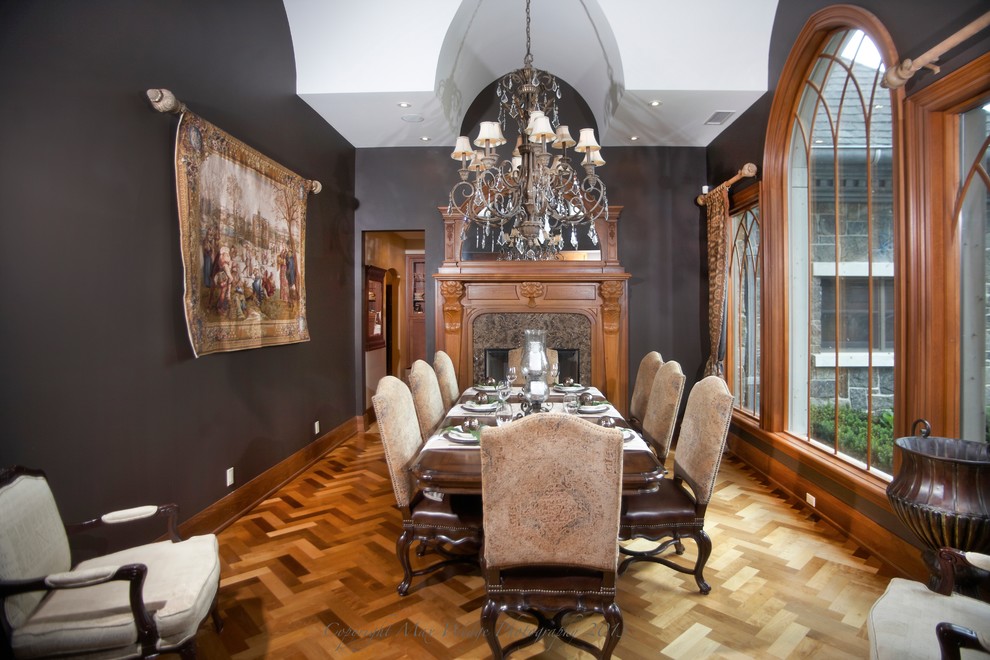 Inspiration pour une salle à manger traditionnelle fermée et de taille moyenne avec un mur gris, un sol en bois brun, une cheminée standard et un manteau de cheminée en bois.