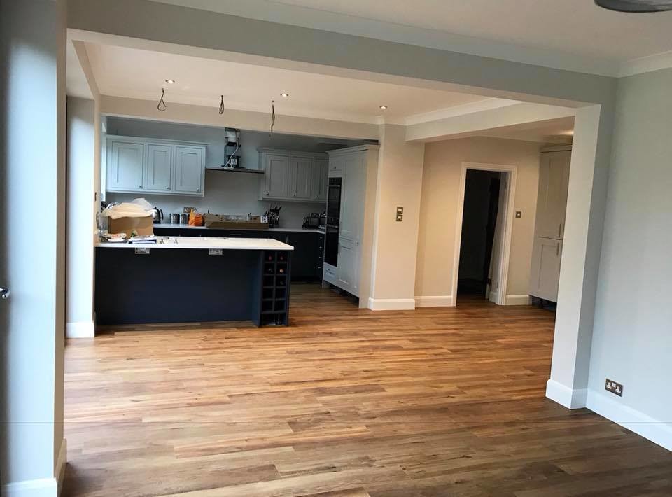 Foto di una sala da pranzo aperta verso la cucina minimalista con pavimento in vinile e pavimento marrone