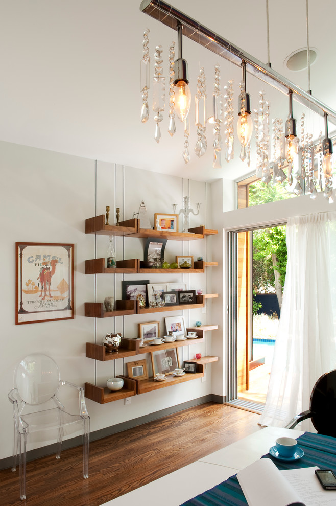 Cette image montre une petite salle à manger ouverte sur le salon minimaliste avec un mur blanc, un sol en bois brun et éclairage.