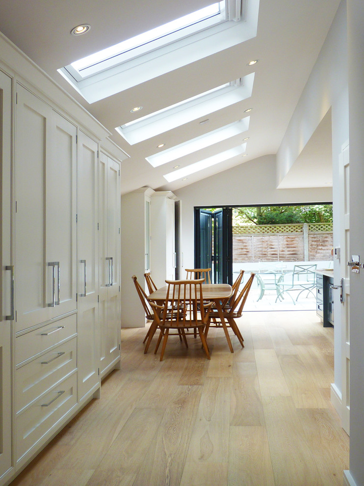 Mittelgroßes, Offenes Klassisches Esszimmer ohne Kamin mit weißer Wandfarbe und hellem Holzboden in London