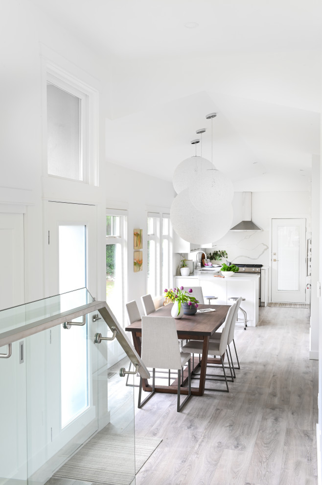 Esempio di una piccola sala da pranzo aperta verso la cucina contemporanea con pareti bianche, pavimento in laminato, pavimento grigio e soffitto a volta