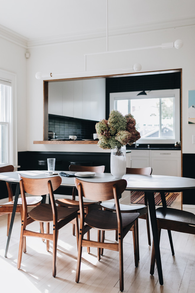 Idées déco pour une salle à manger ouverte sur la cuisine scandinave de taille moyenne avec un mur blanc, parquet clair, une cheminée standard, un manteau de cheminée en pierre et un sol blanc.