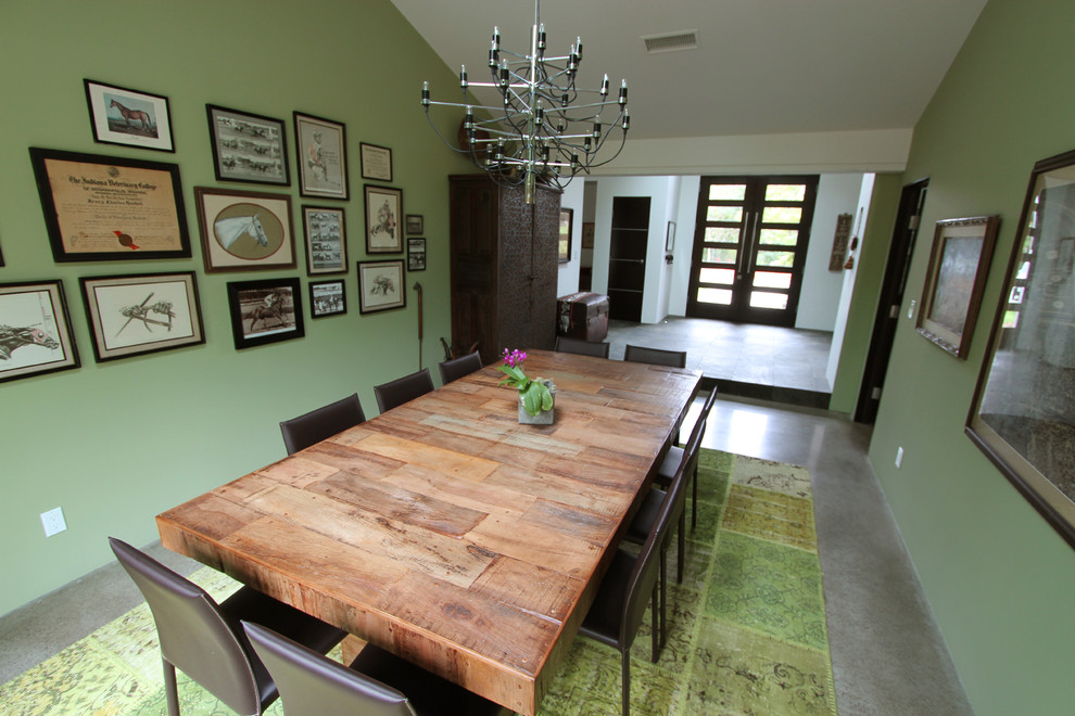 Ispirazione per una sala da pranzo aperta verso il soggiorno stile rurale con pareti verdi, pavimento in cemento e nessun camino