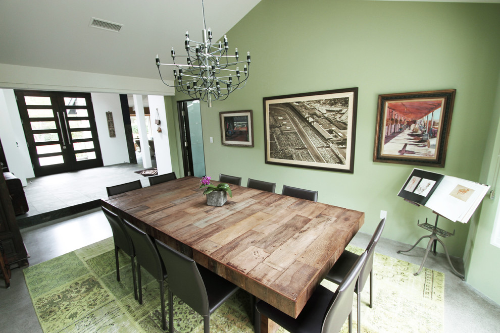 Foto di una sala da pranzo design con pareti verdi, pavimento in cemento e nessun camino