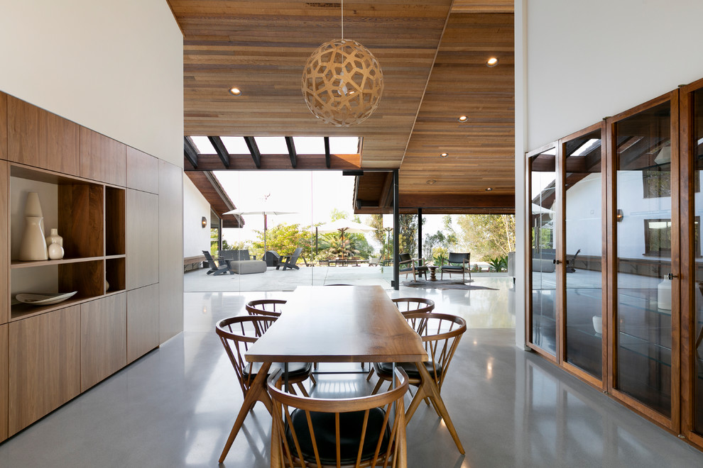 Midcentury open plan dining room in Los Angeles with white walls, concrete flooring, no fireplace and grey floors.