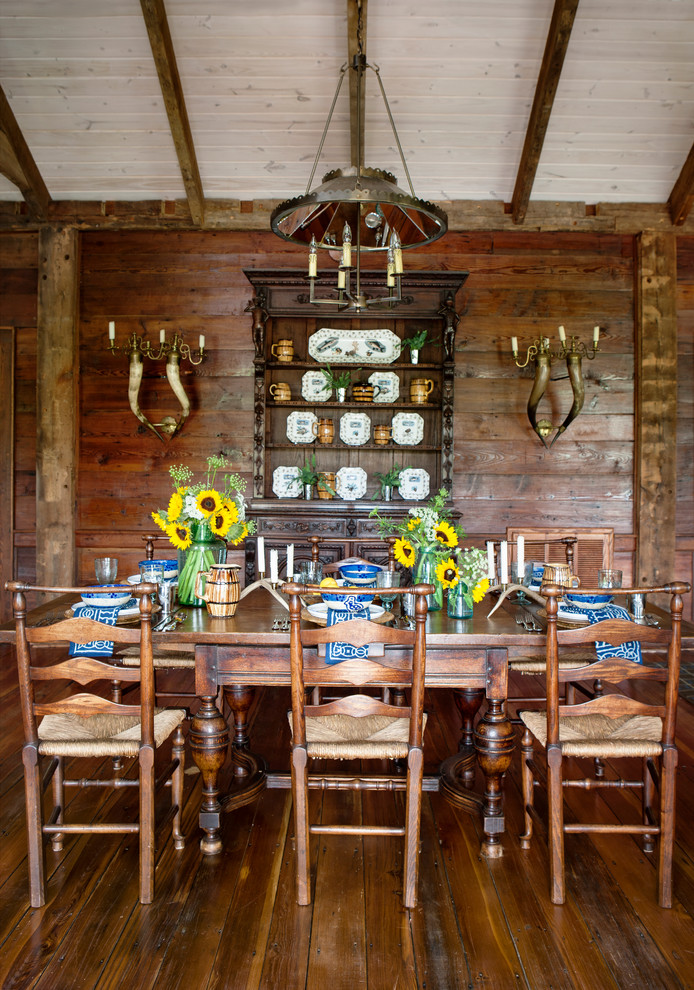 Immagine di una grande sala da pranzo aperta verso la cucina country con pareti marroni e parquet chiaro