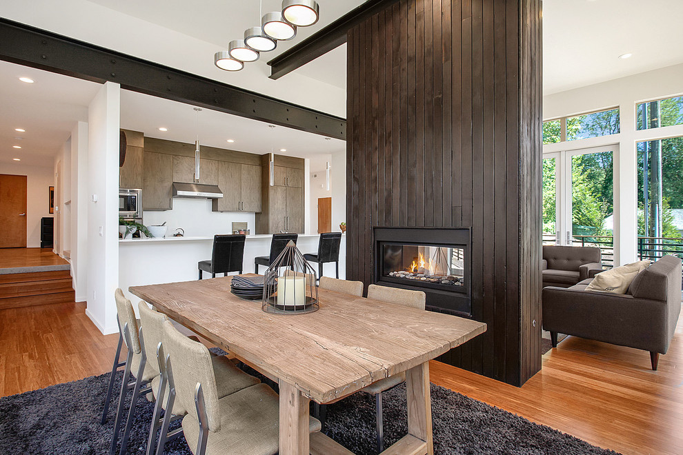 Стильный дизайн: гостиная-столовая в современном стиле с полом из бамбука и двусторонним камином - последний тренд