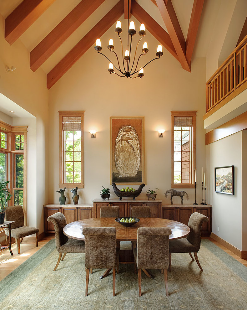 Diseño de comedor de estilo americano abierto con paredes beige, suelo de madera clara, todas las chimeneas y marco de chimenea de piedra