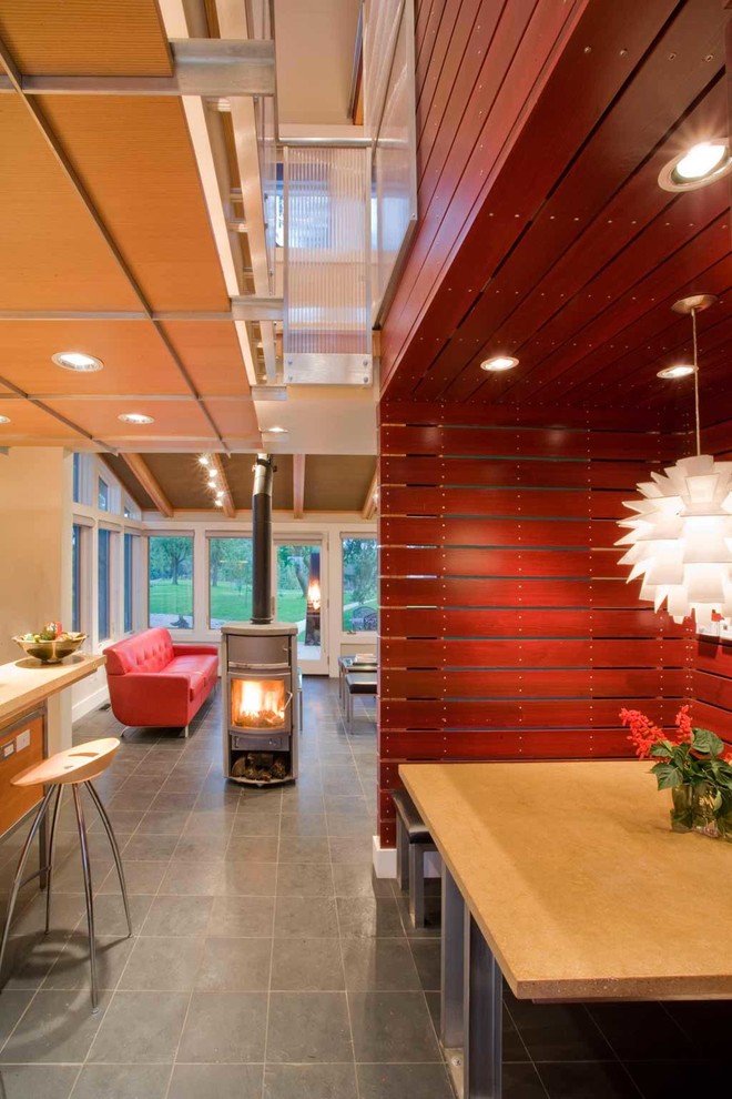 Idee per una piccola sala da pranzo aperta verso la cucina country con pareti rosse, pavimento in ardesia e stufa a legna