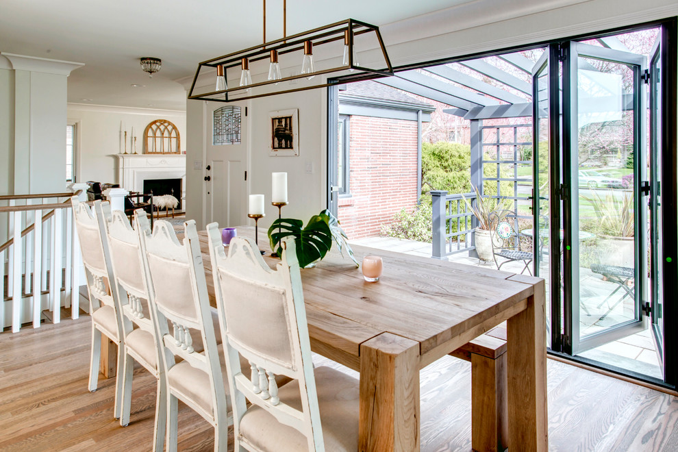 Foto di una sala da pranzo aperta verso la cucina tradizionale con pareti bianche, parquet chiaro e pavimento beige