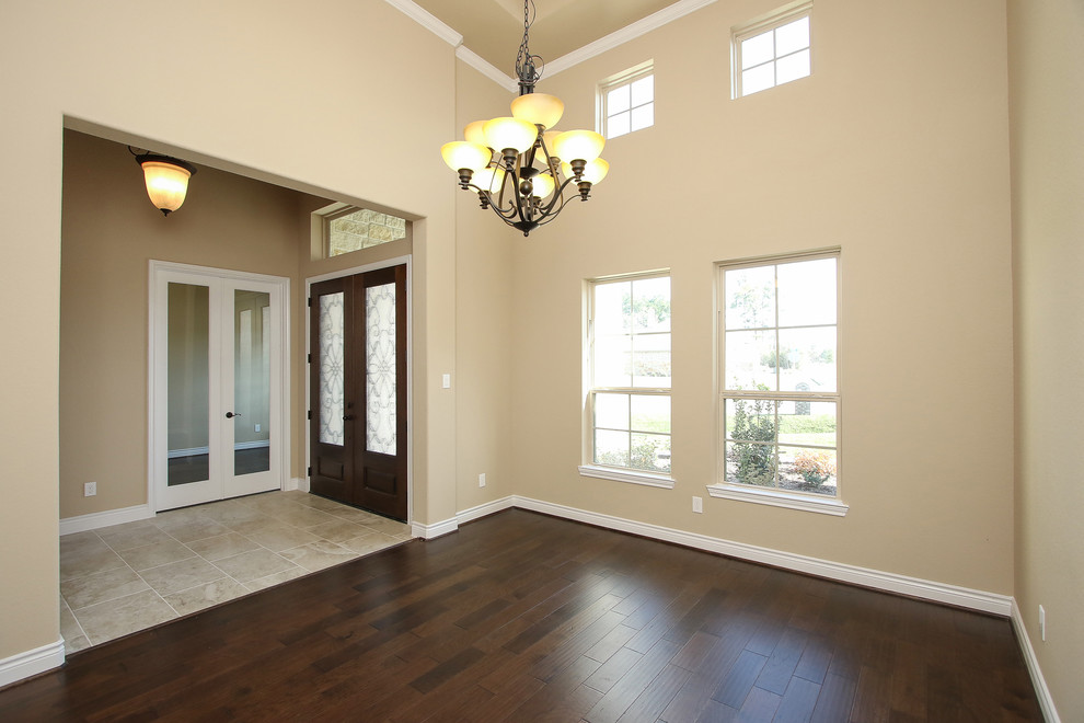 Geschlossenes, Großes Klassisches Esszimmer mit beiger Wandfarbe, dunklem Holzboden und braunem Boden in Houston