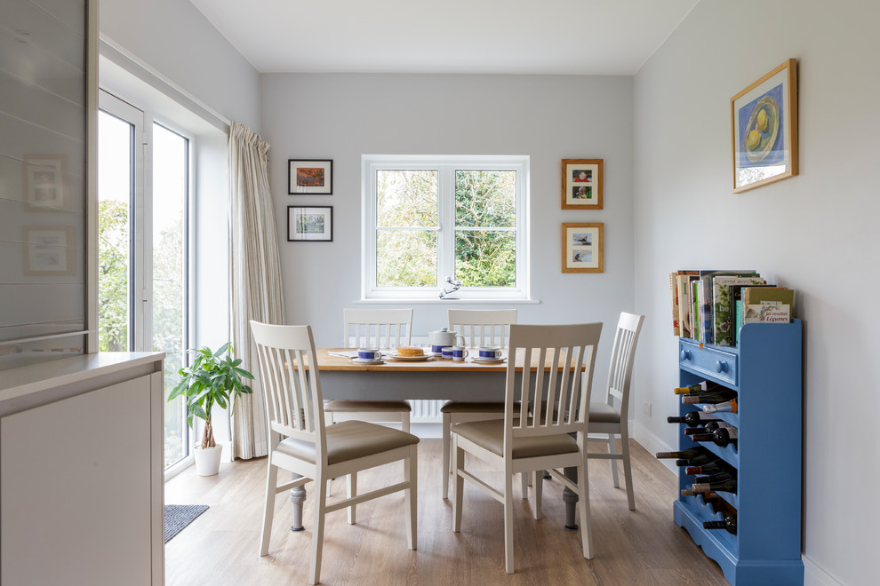 Cette image montre une salle à manger ouverte sur la cuisine traditionnelle avec un mur gris et parquet clair.