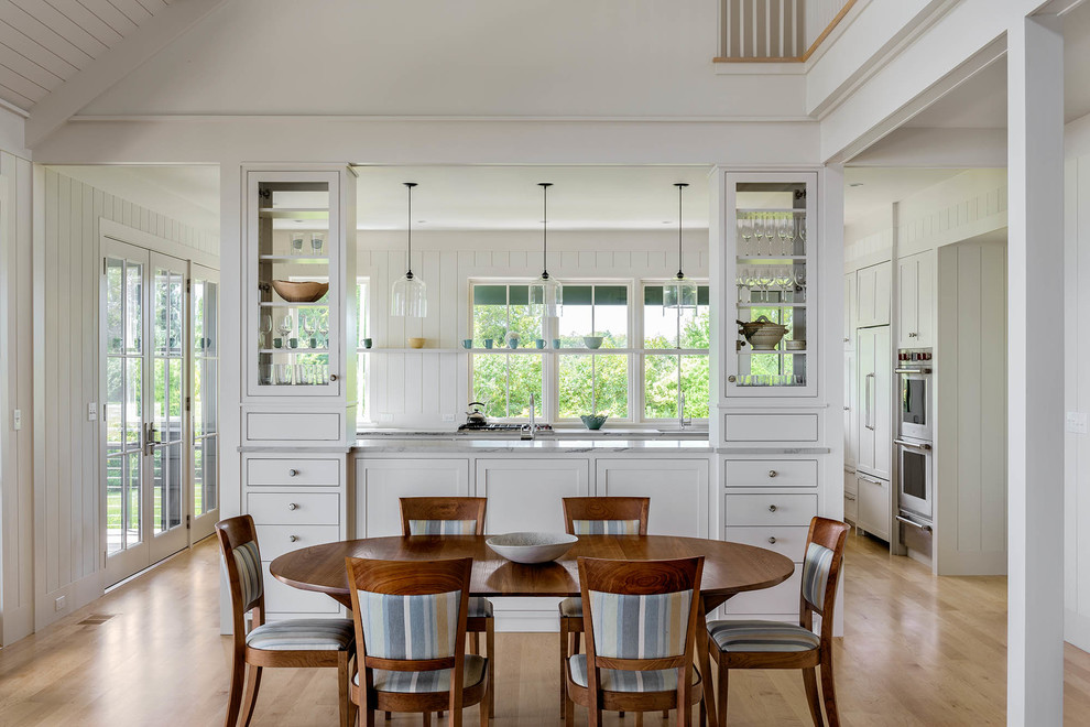 Medium sized beach style kitchen/dining room in Portland Maine with white walls and light hardwood flooring.