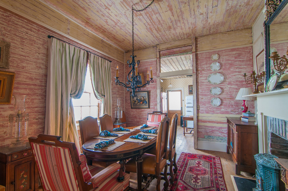 Foto di una sala da pranzo boho chic chiusa con pareti multicolore, pavimento in legno massello medio, camino classico e cornice del camino in mattoni