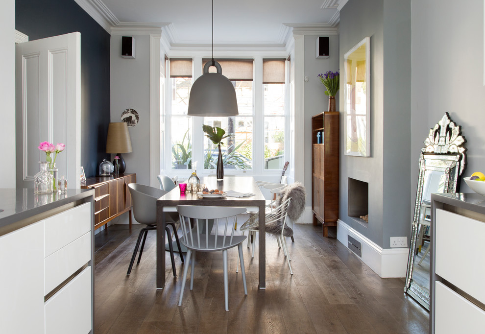 Inspiration for a medium sized contemporary kitchen/dining room in London with multi-coloured walls, dark hardwood flooring, a standard fireplace, a plastered fireplace surround, brown floors and feature lighting.