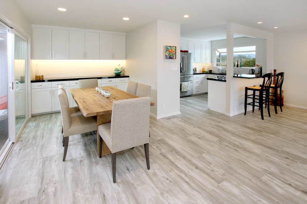 Inspiration pour une grande salle à manger ouverte sur la cuisine minimaliste avec un mur blanc, un sol en carrelage de porcelaine, cheminée suspendue, un manteau de cheminée en carrelage et un sol gris.