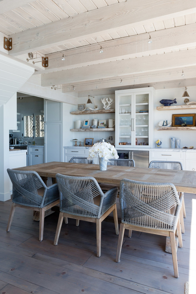 Cette image montre une petite salle à manger ouverte sur la cuisine marine avec un mur blanc, un sol en bois brun, une cheminée standard, un manteau de cheminée en brique et un sol gris.