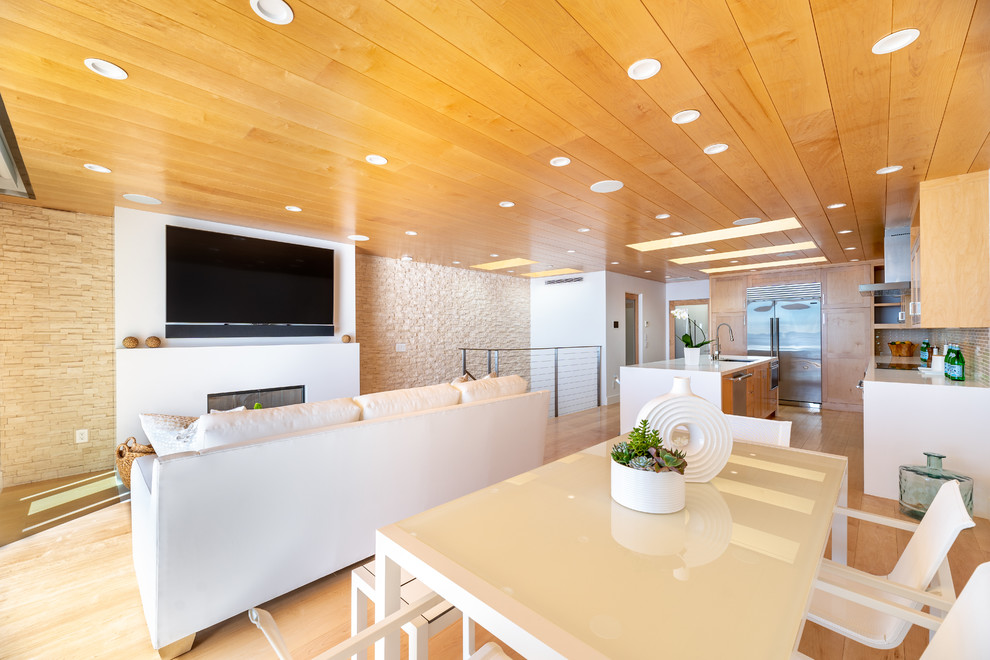 Offenes, Geräumiges Modernes Esszimmer mit weißer Wandfarbe, hellem Holzboden, Kamin, Kaminumrandung aus Stein und gelbem Boden in Los Angeles