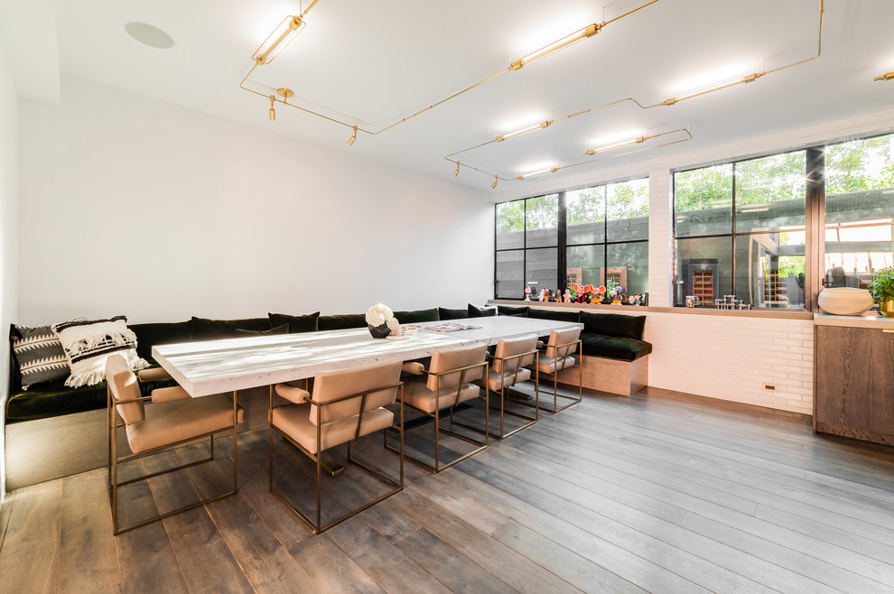 Foto di un'ampia sala da pranzo aperta verso la cucina minimal con pareti bianche, pavimento grigio e pavimento in legno massello medio