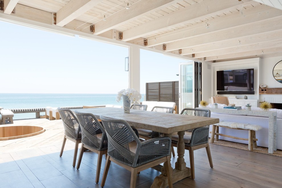 Diseño de comedor costero de tamaño medio abierto con paredes blancas y suelo de madera en tonos medios