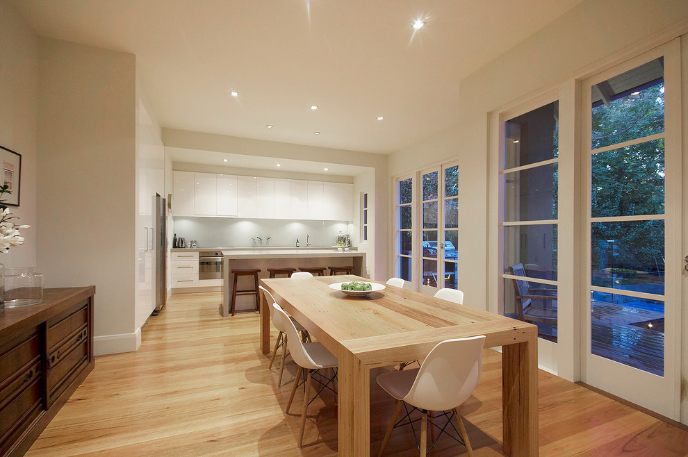 Réalisation d'une grande salle à manger ouverte sur la cuisine design avec un mur blanc et parquet clair.