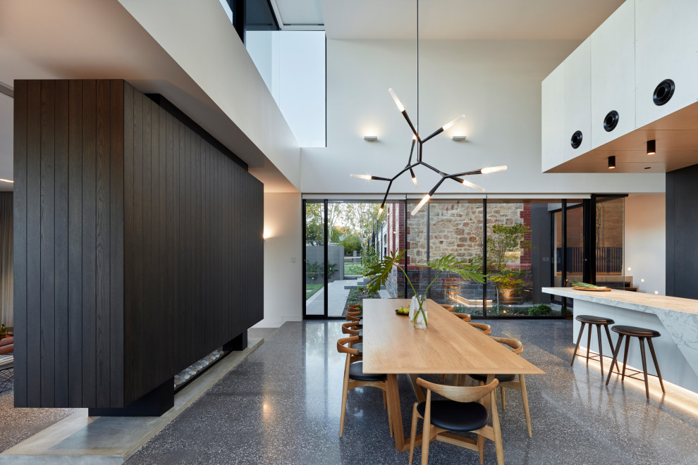 Idée de décoration pour une salle à manger ouverte sur le salon design avec un mur blanc et un sol gris.