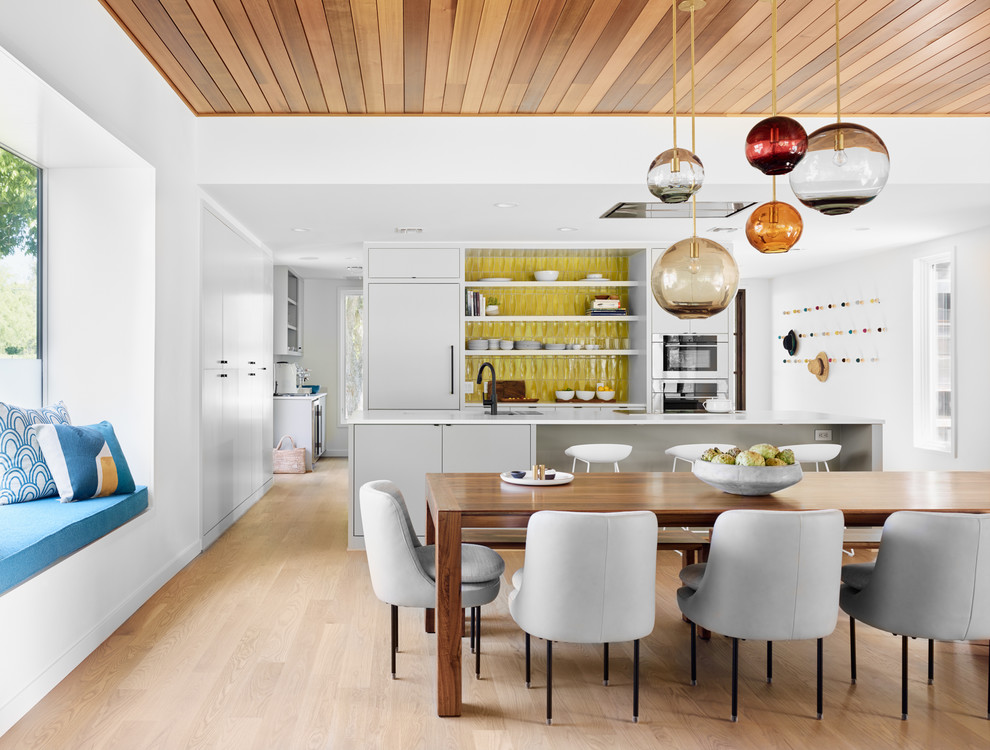 Cette photo montre une salle à manger ouverte sur la cuisine tendance avec un mur blanc, parquet clair et un sol beige.