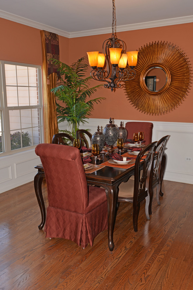 Idée de décoration pour une salle à manger ouverte sur la cuisine tradition de taille moyenne avec un mur orange et un sol en bois brun.