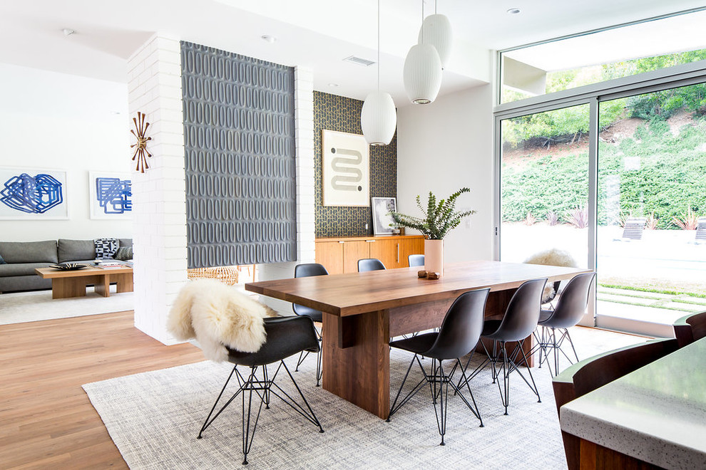 Design ideas for a midcentury open plan dining room in Los Angeles with white walls, medium hardwood flooring, a two-sided fireplace, a tiled fireplace surround and brown floors.
